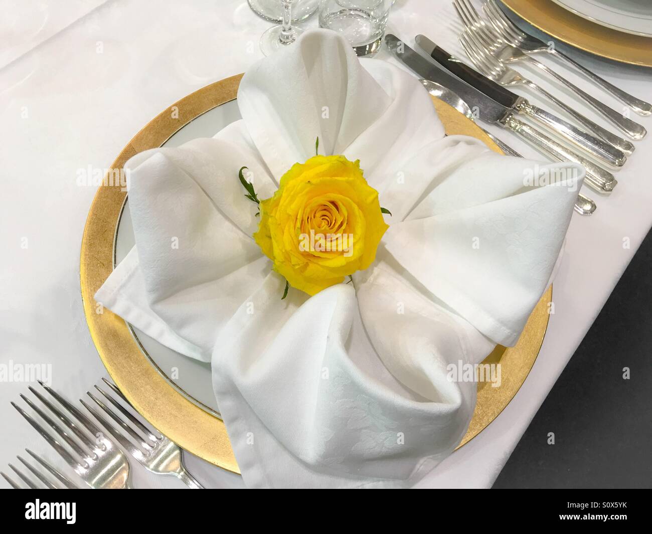 Table place setting with yellow rose in centre Stock Photo