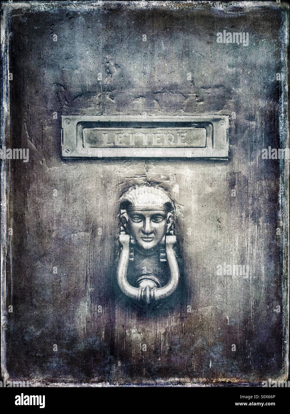 Door knocker in the shape of pharaoh and letter plate on the front door in Italy - Smartphone Captured Stock Image