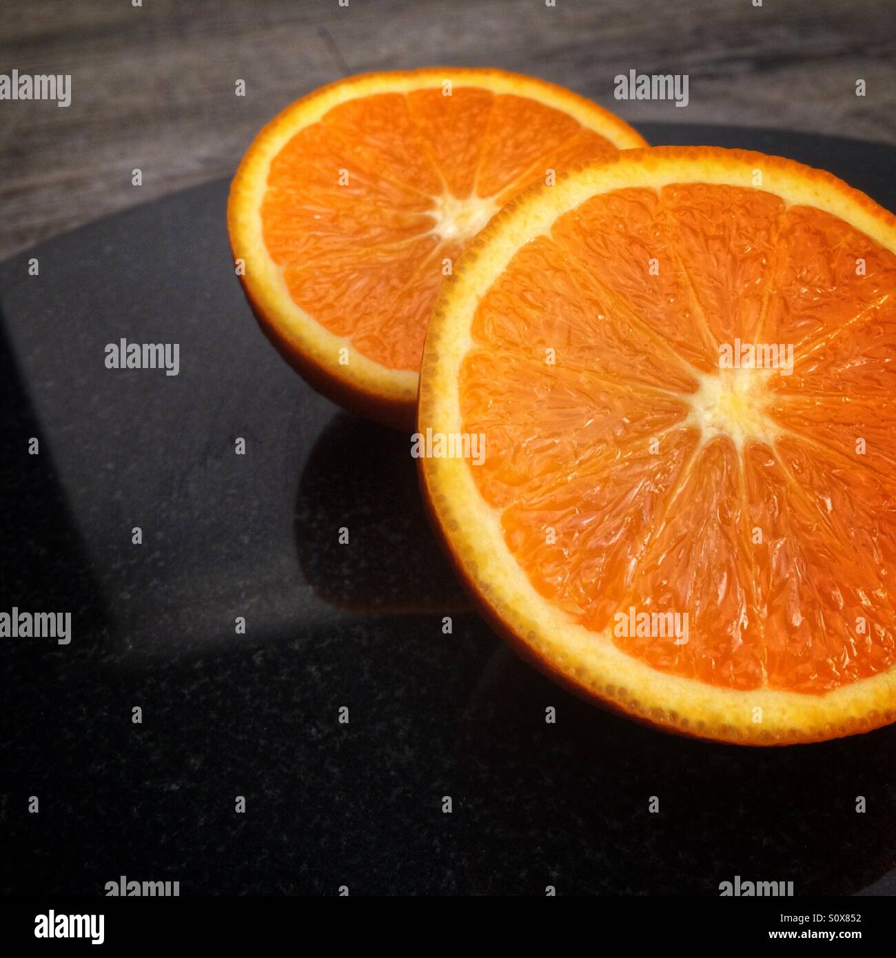 Orange halves on black granite slab Stock Photo