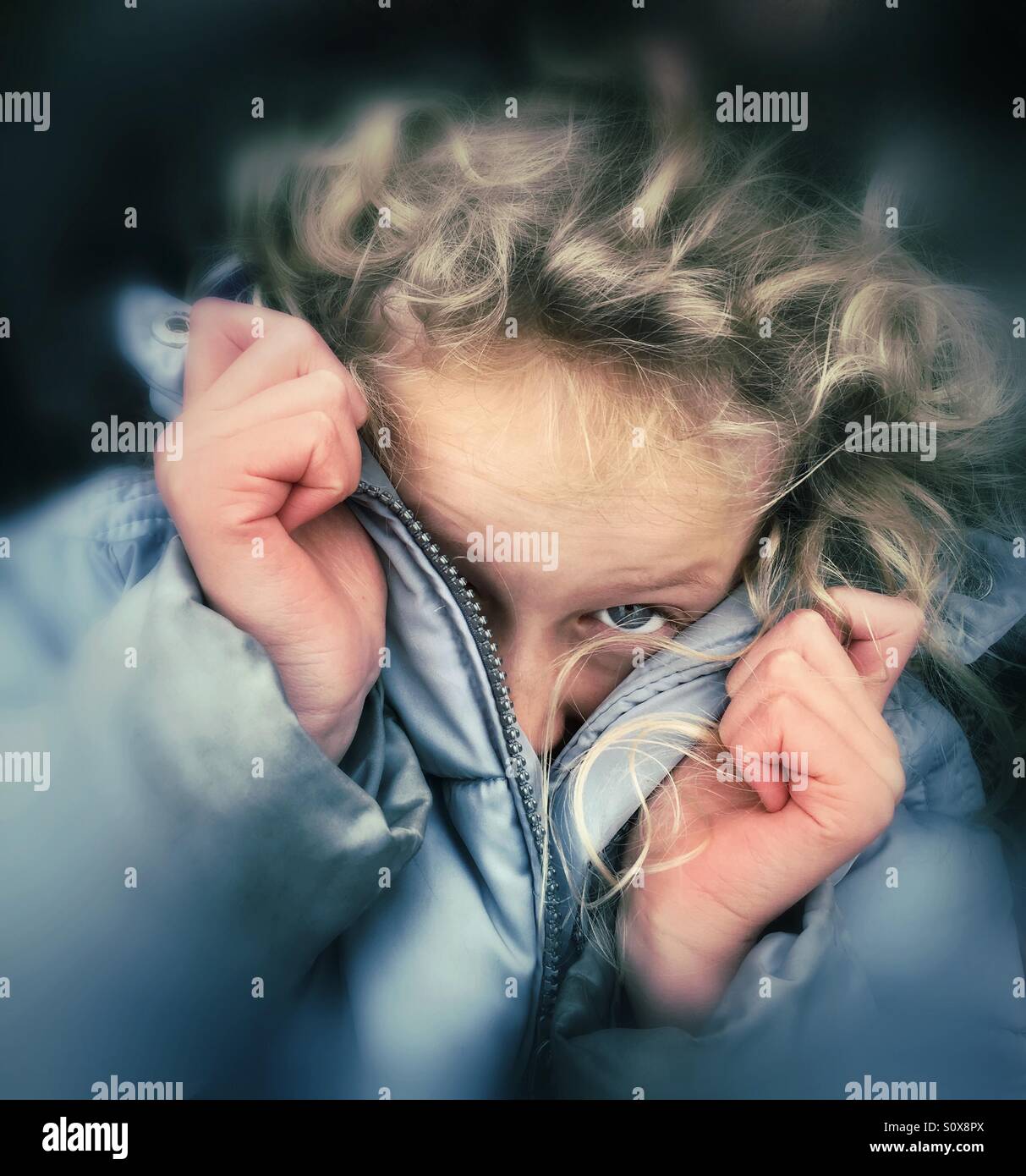 Young girl peering out from her warm winter coat Stock Photo