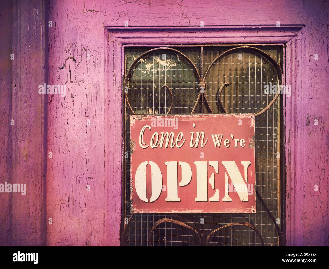 Come in we're open sign on an old wooden door Stock Photo