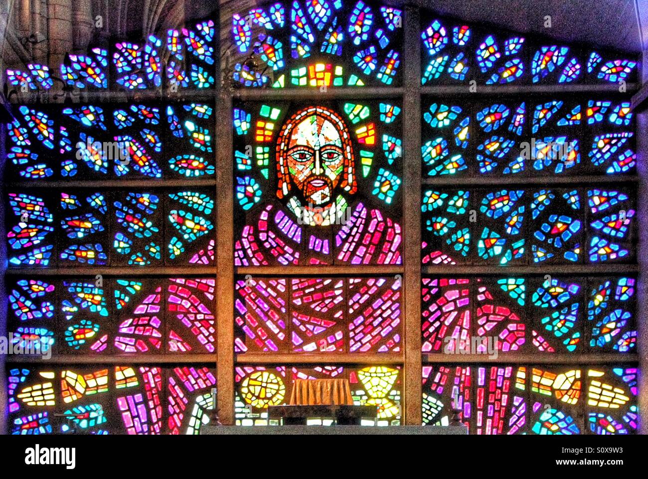 A stain glass window of Jesus with his arms opened wide. A religious image of Jesus Christ in colourful glass. - Smartphone Captured Stock Image
