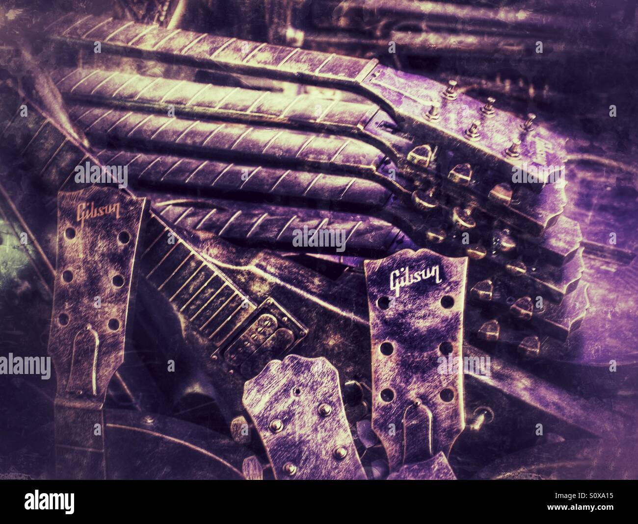 A pile of discarded Gibson electric guitars. Old musical instruments piled up in a heap with a purple hue. Stock Photo