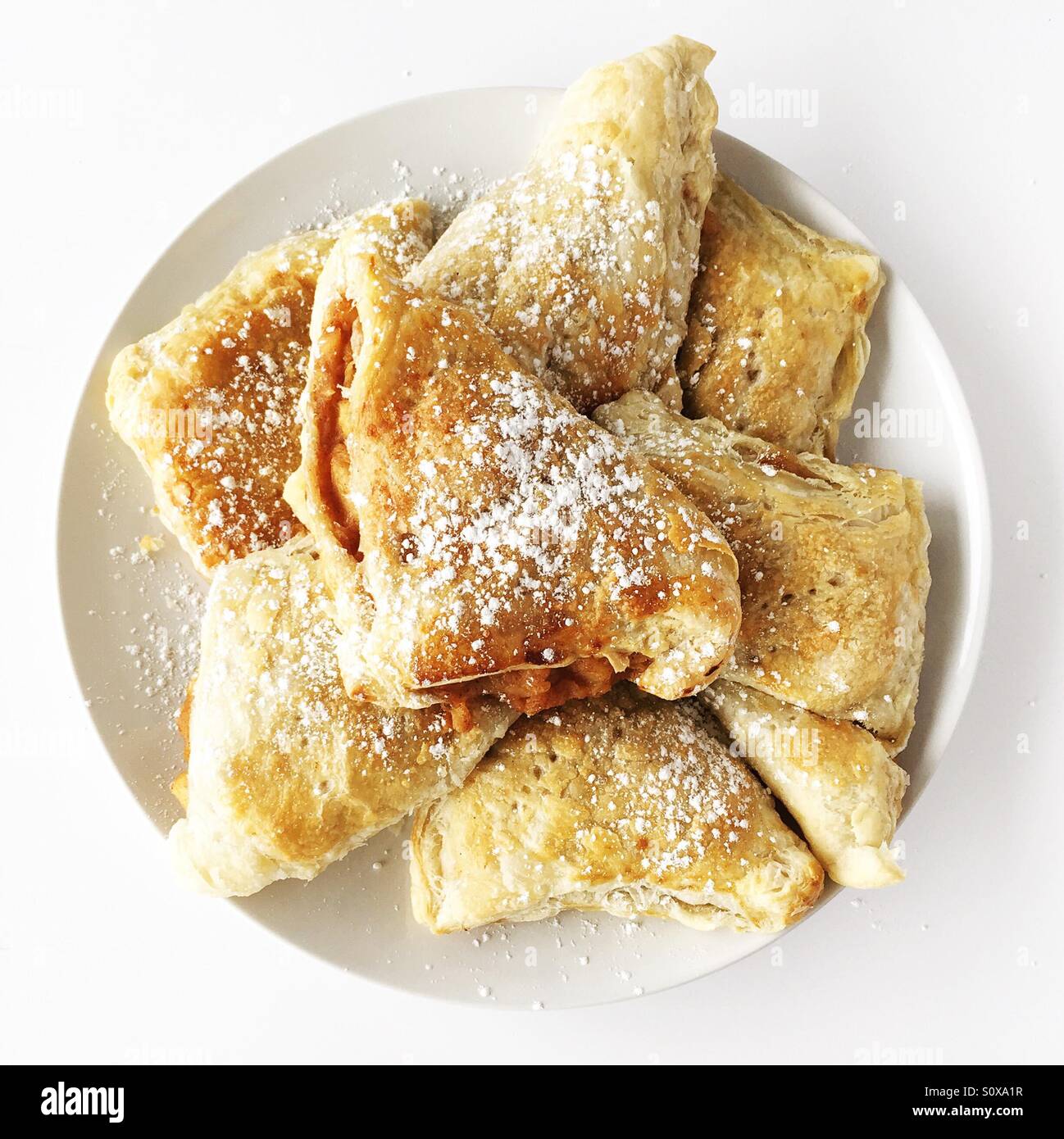 Freshly baked apple turnover pastries on a white plate. Photographed from above, square crop. - Smartphone Captured Stock Image