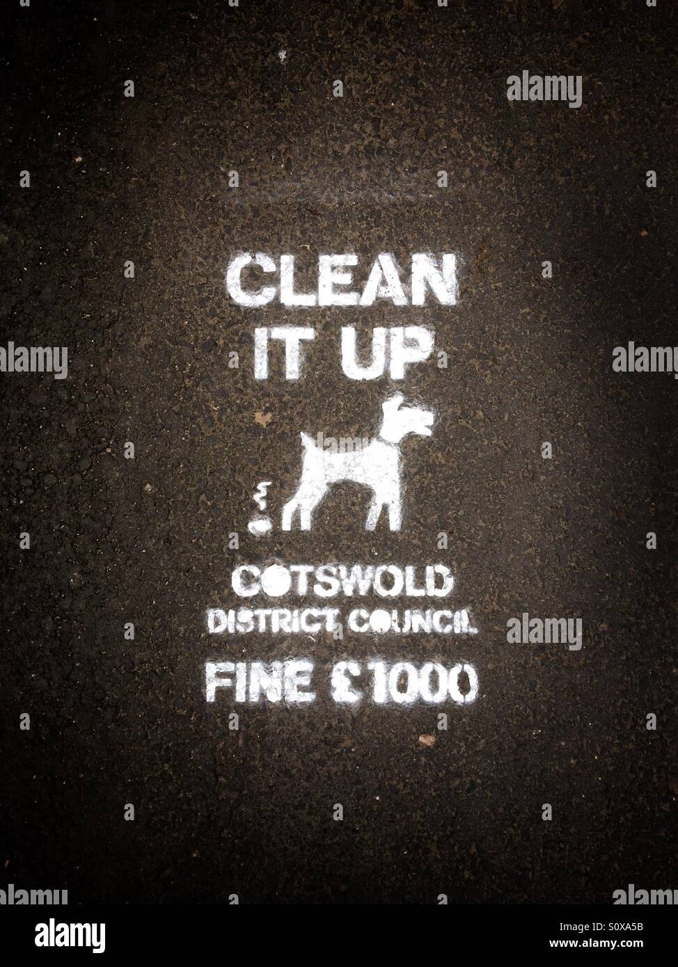 Clean it up sign on the pavement asking dog owners to clear up their dog's mess - Smartphone Captured Stock Image