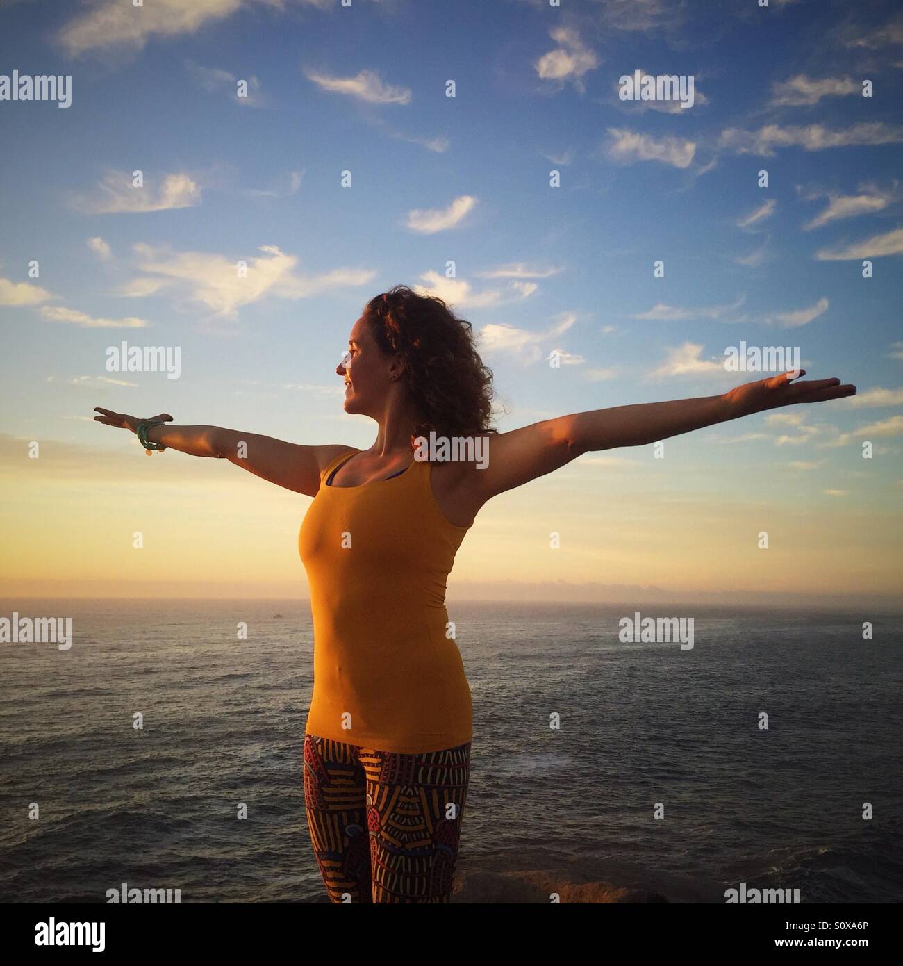 Woman welcoming sun with open arms Stock Photo