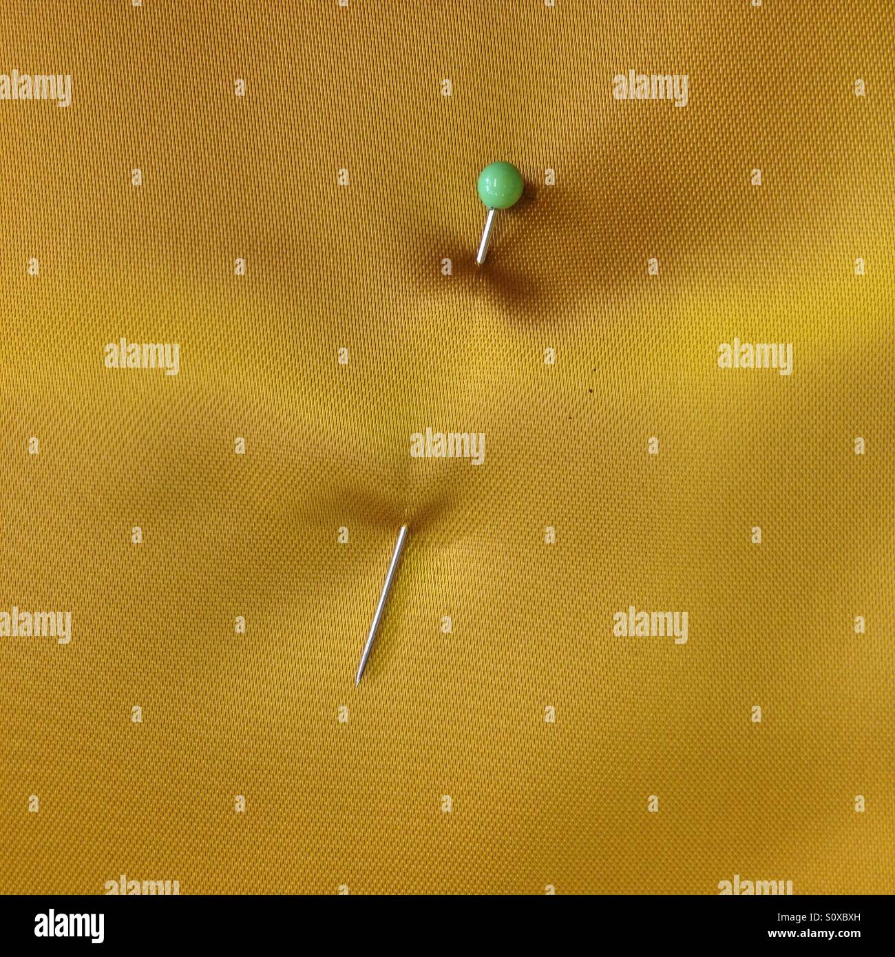 Sewing pin in yellow satin Stock Photo