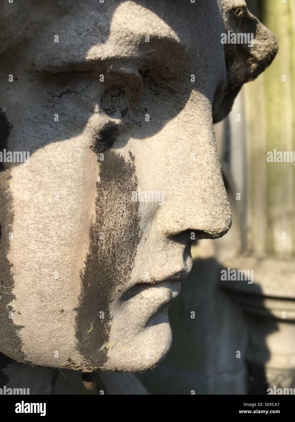 Tombstone sculpture with acid rain tears. Brompton cemetery, Kensington, London, England - Smartphone Captured Stock Image