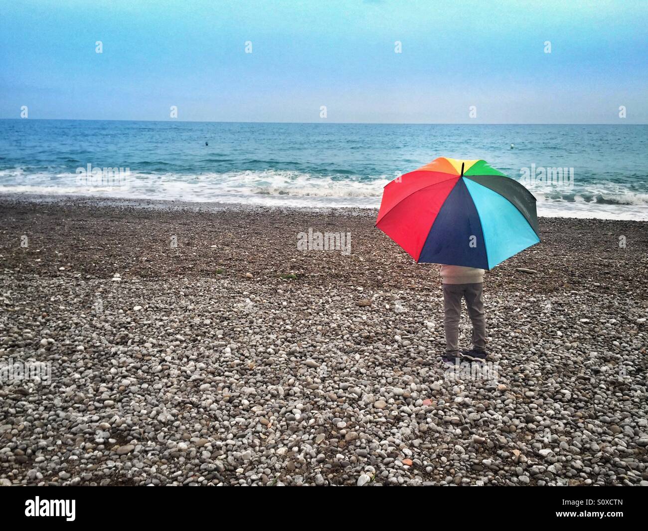 Girl on the beach with a colorful umbrella Stock Photo