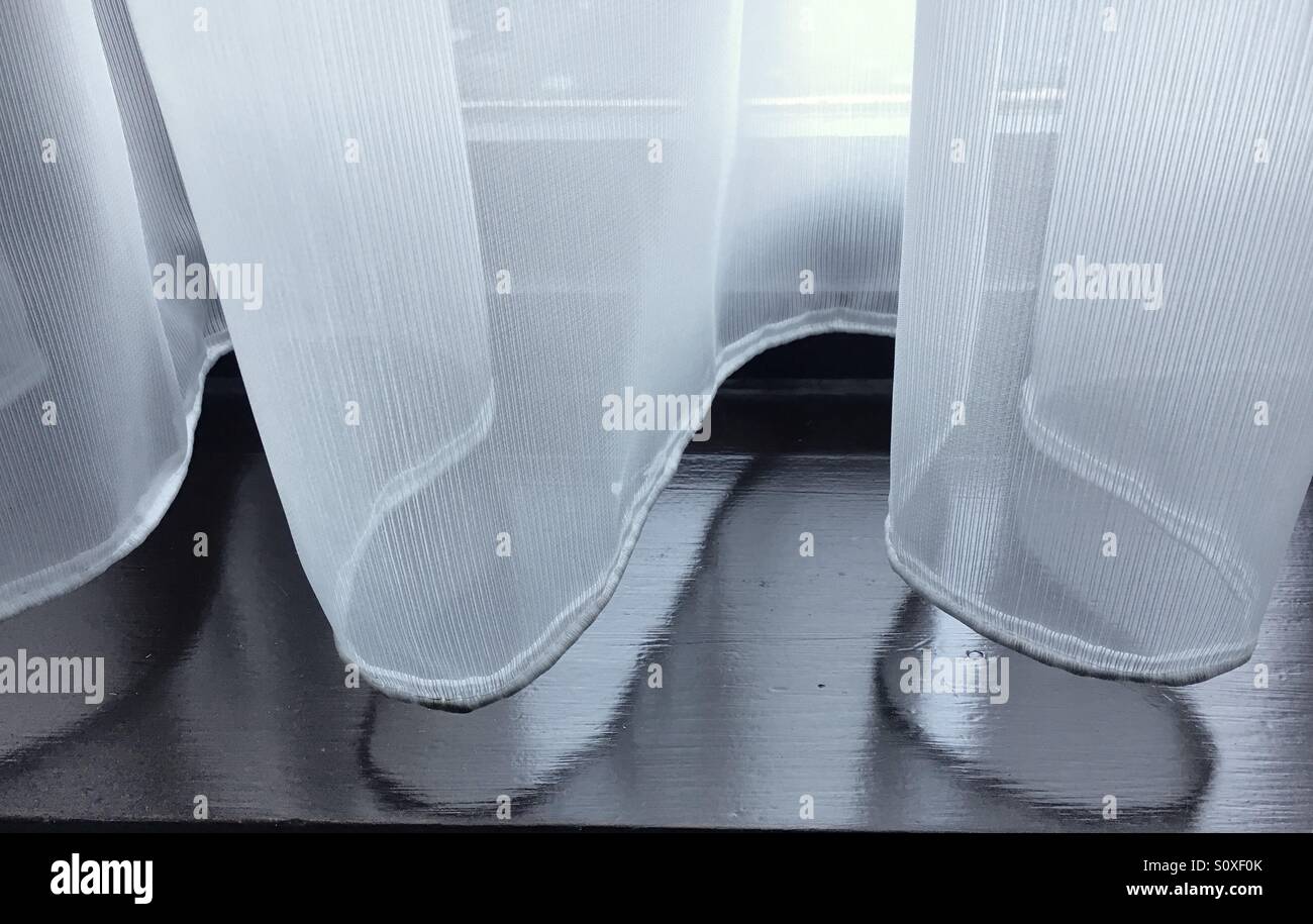 Part of a net curtain above a wooden windowsill - Smartphone Captured Stock Image