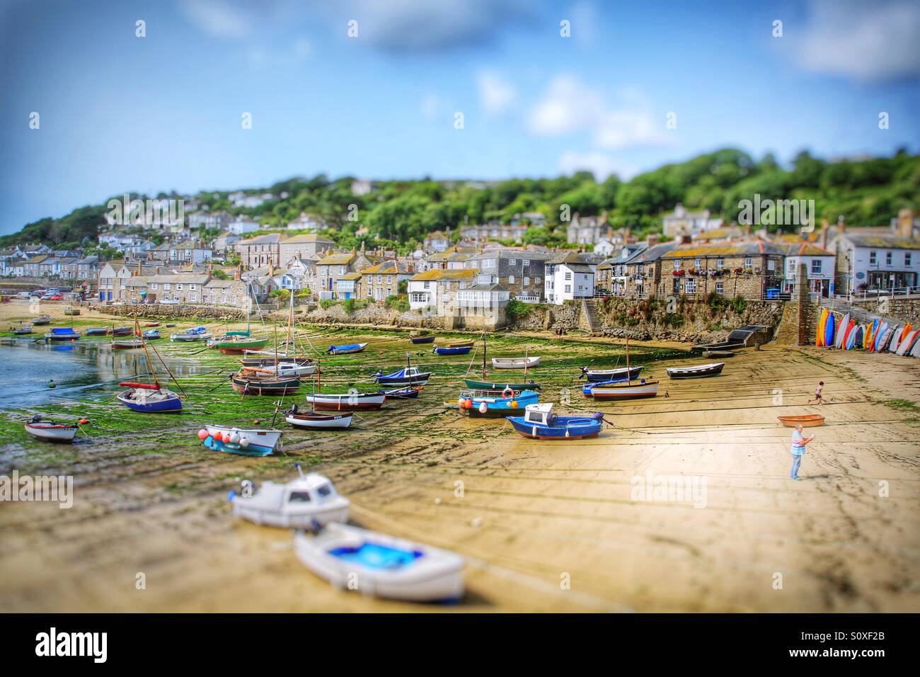 The quaint Cornish fishing village and harbour of Mousehole in Cornwall. Beached fishing boats in a busy harbour. - Smartphone Captured Stock Image