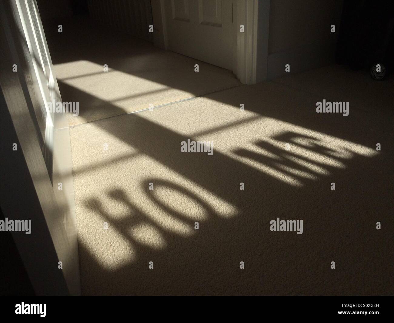 Letter ornaments cast a shadow spelling 'home' on the floor - Smartphone Captured Stock Image