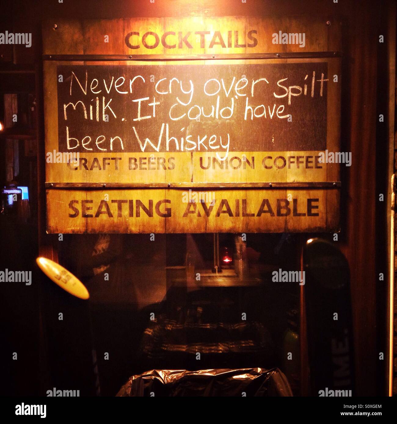 A humorous slogan on a chalkboard outside a pub next to King's Cross Station in London: Never cry over spilt milk, it could have been Whiskey - Smartphone Captured Stock Image