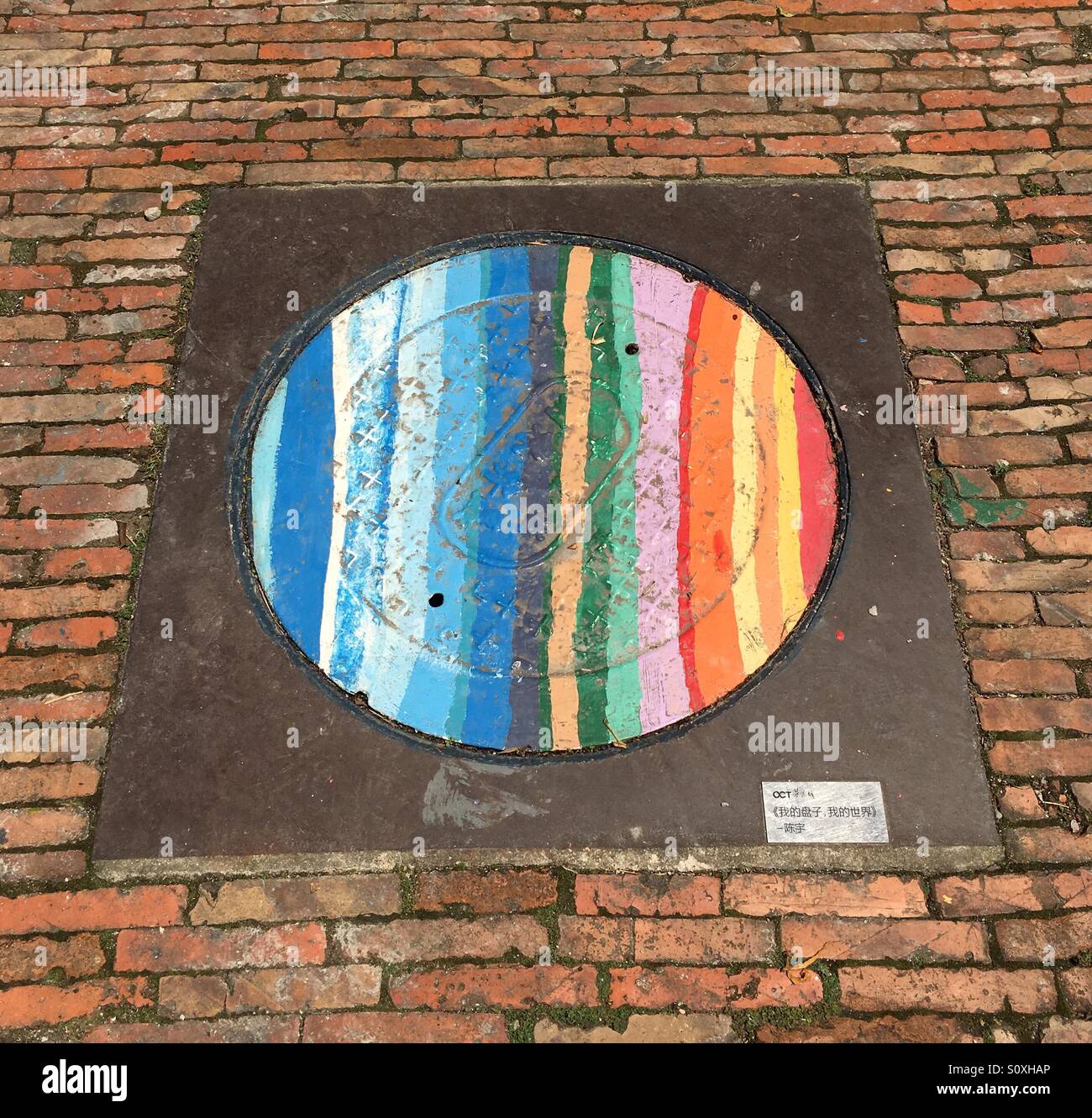 Manhole Cover Painted in Rainbow Colours - Shenzhen, China Stock Photo