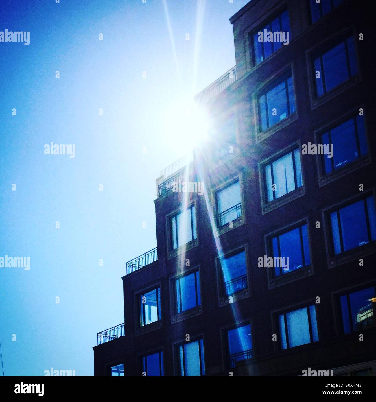 Bright sun shining from behind building Stock Photo