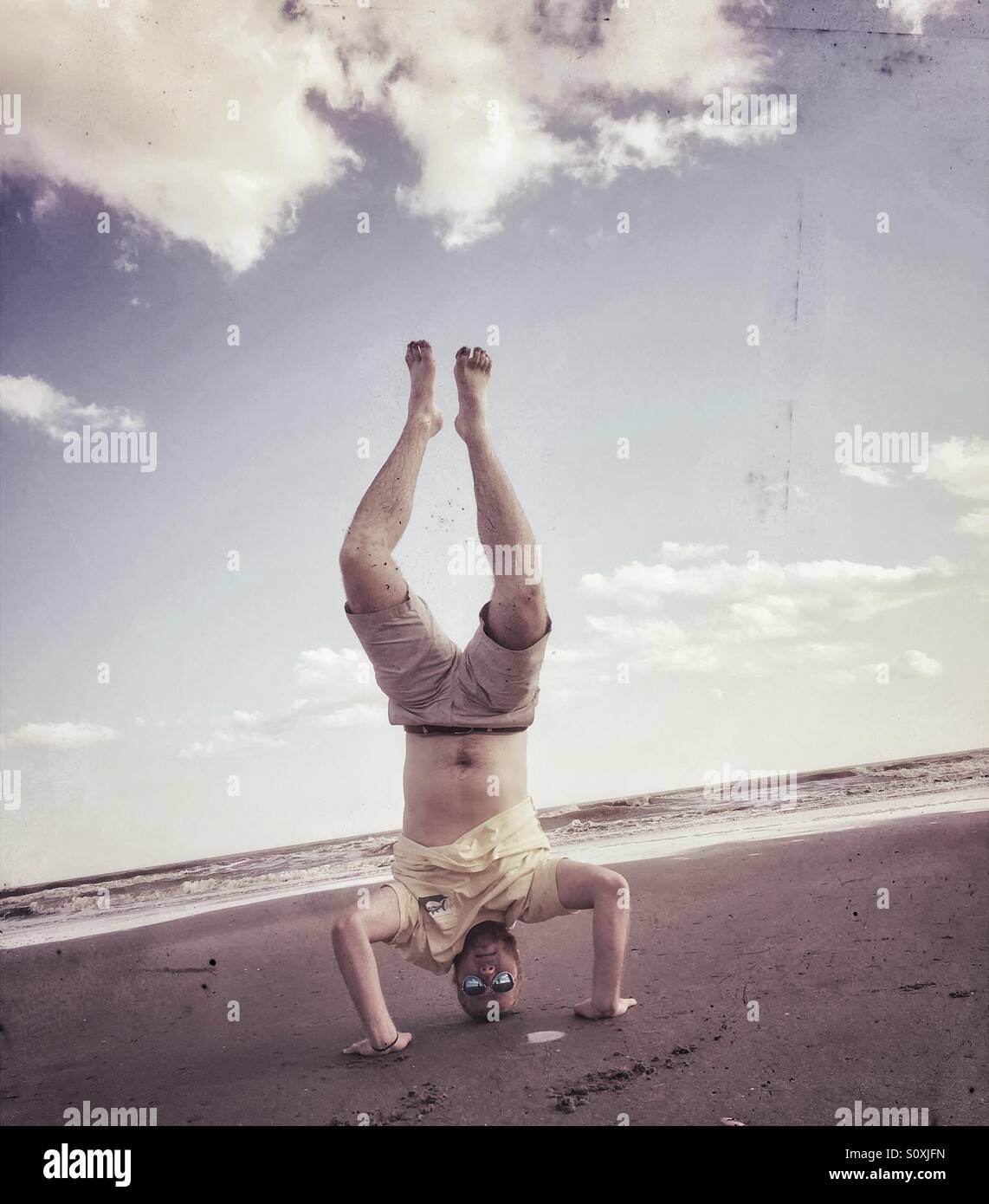 Guy doings handstand on beach, Isle of Palms, South Carolina Stock Photo