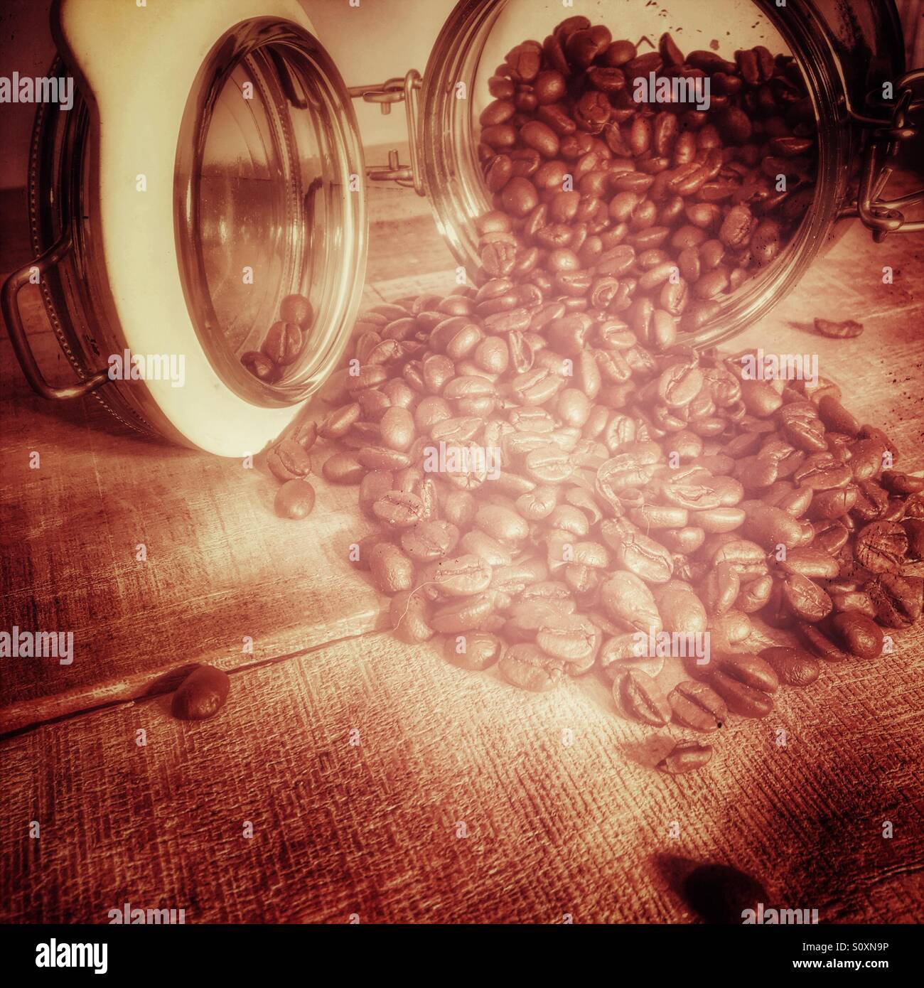 Fresh roasted arabica coffee beans pouring from a glass Kilner type coffee jar. Stock Photo