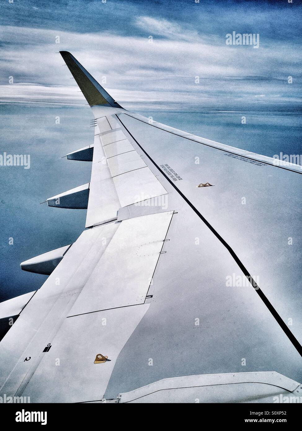 View of an airplane wing over the clouds from the window Stock Photo