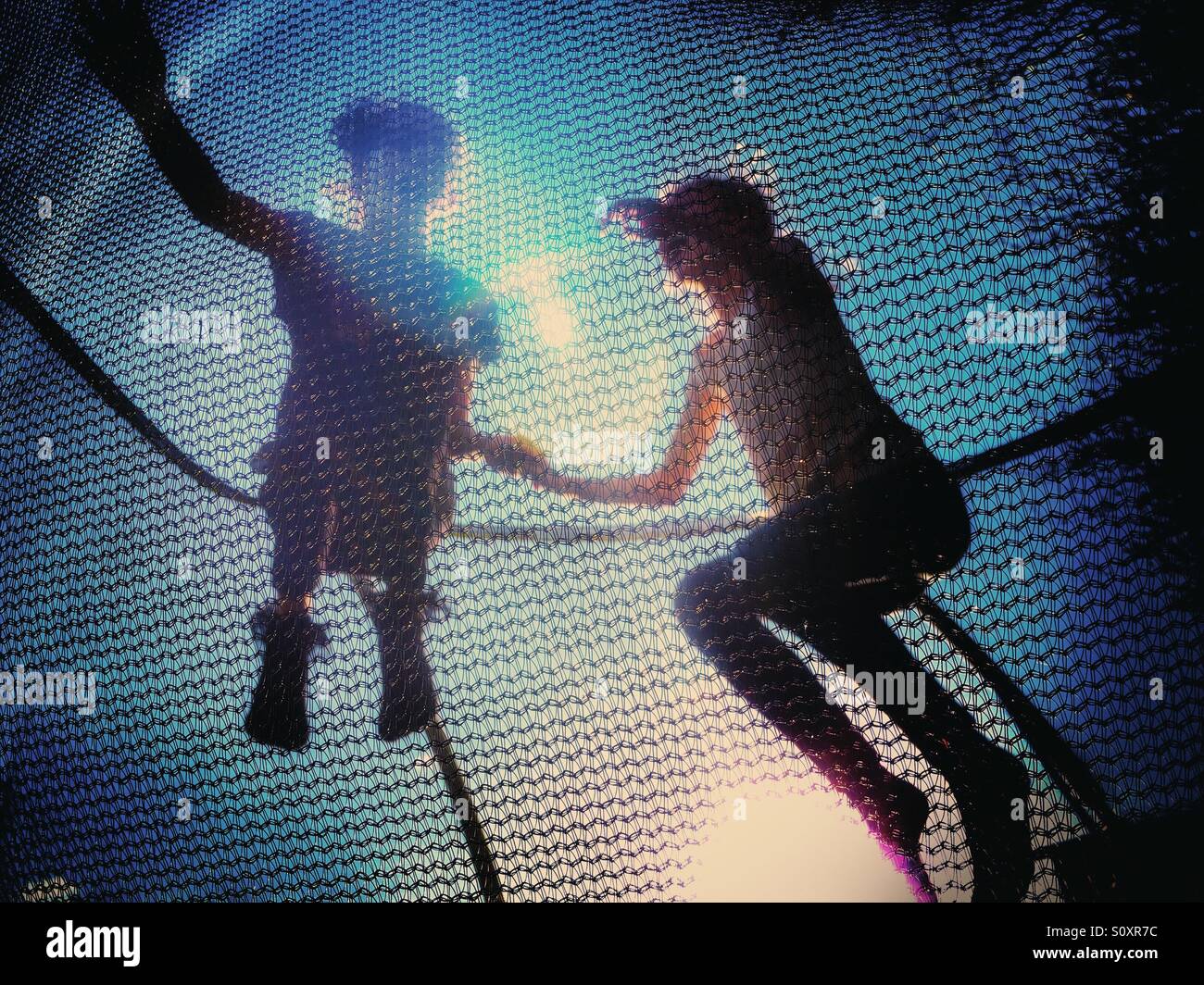 Two children having fun bouncing on trampoline - Smartphone Captured Stock Image