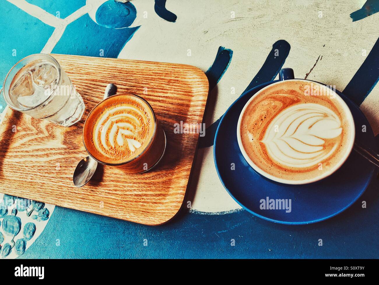 View from above of a table with two coffees, glass of water and wooden tray Stock Photo