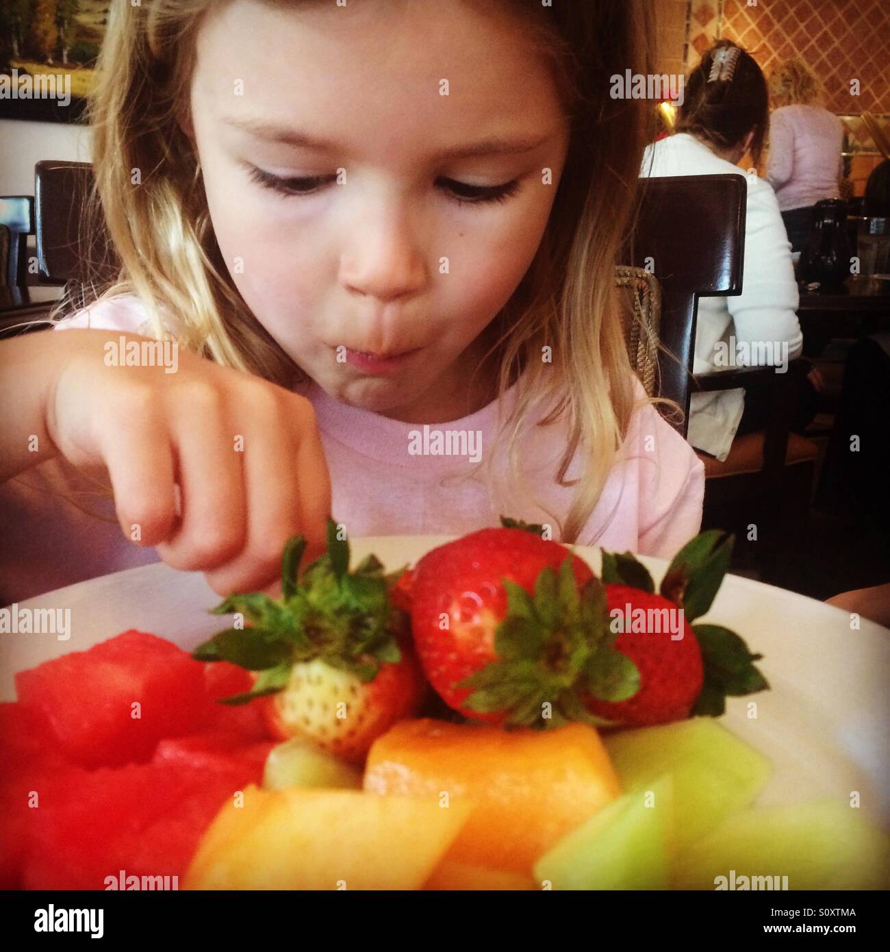 Little girl eating breakfast of fruit Stock Photo Alamy