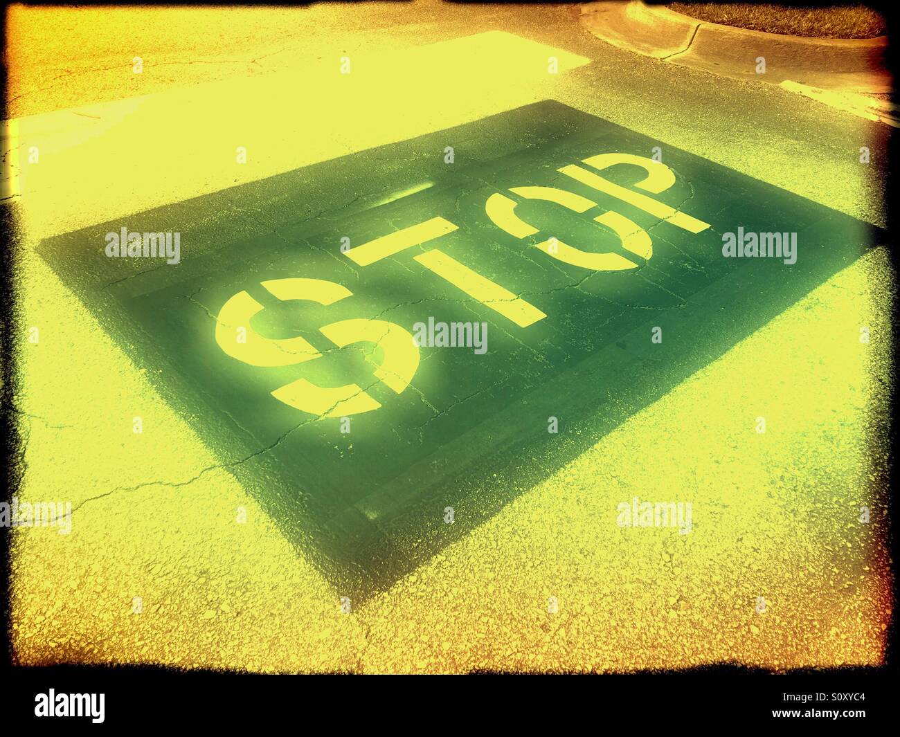 The word STOP painted on a road in a parking lot. Stock Photo