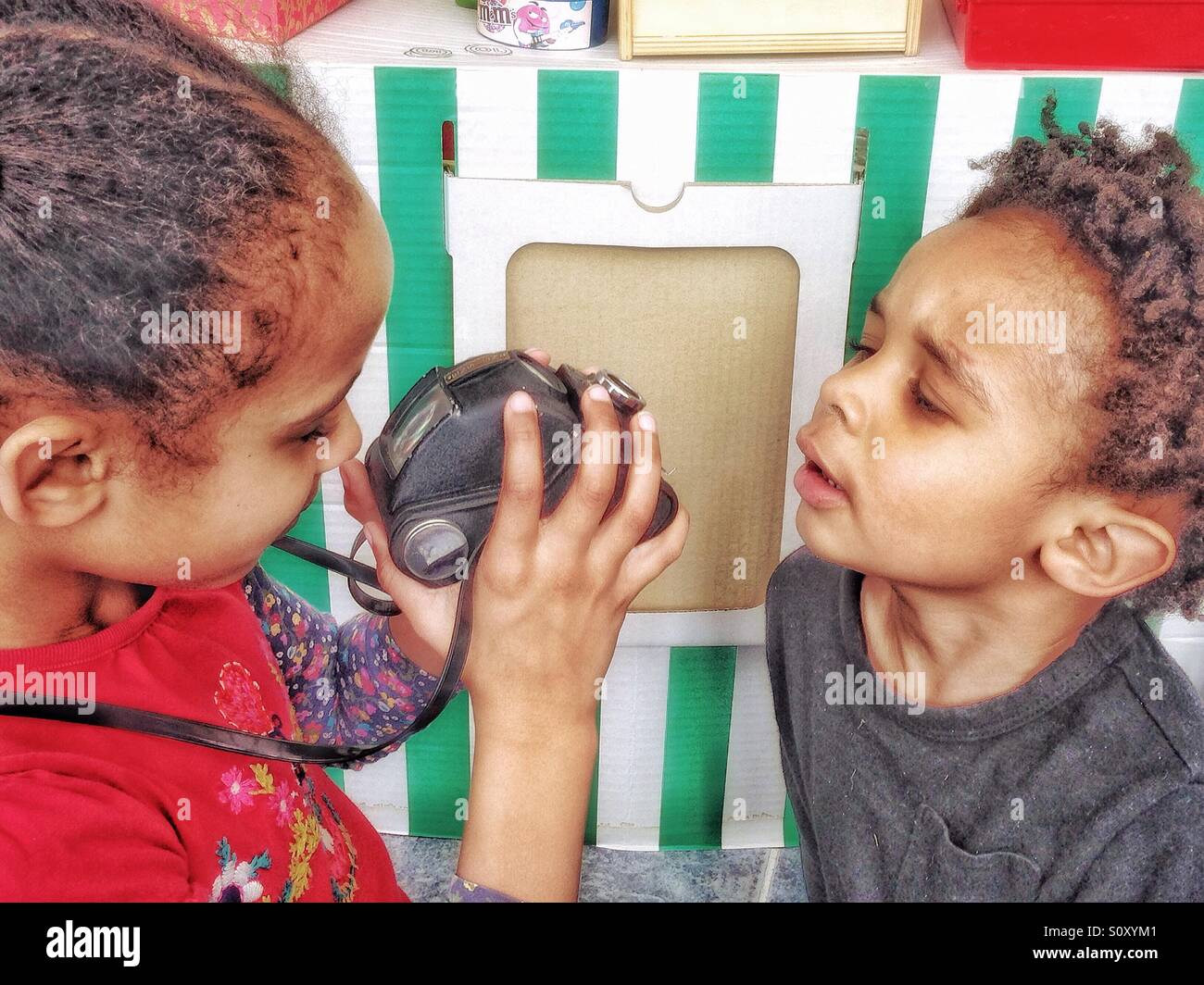 Two children playing with a vintage camera. Stock Photo