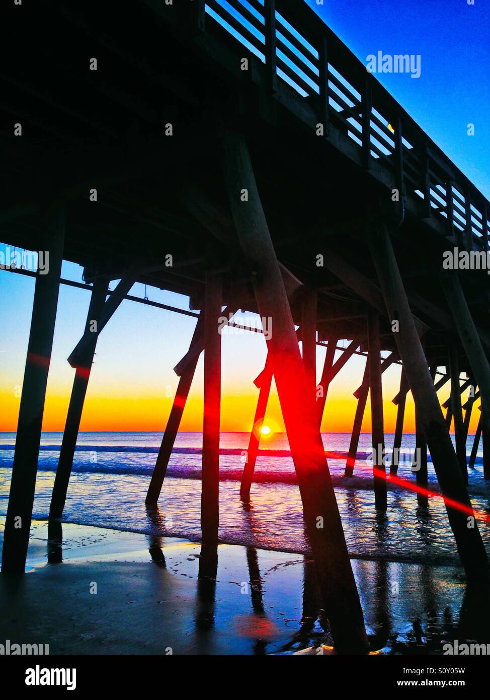 Sunrise with lens flare under the pier at Myrtle Beach South Carolina Stock Photo
