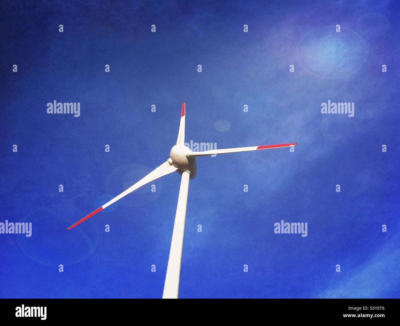 Wind turbine against clear blue sky. Lens flare effect added - Smartphone Captured Stock Image