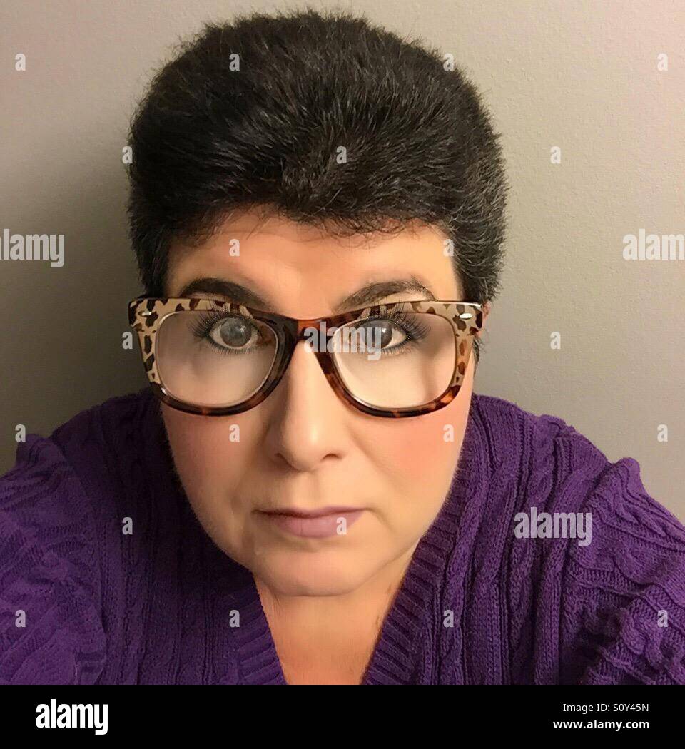 A portrait of a middle aged woman with dark hair and very large eyeglasses taking a selfie Stock Photo