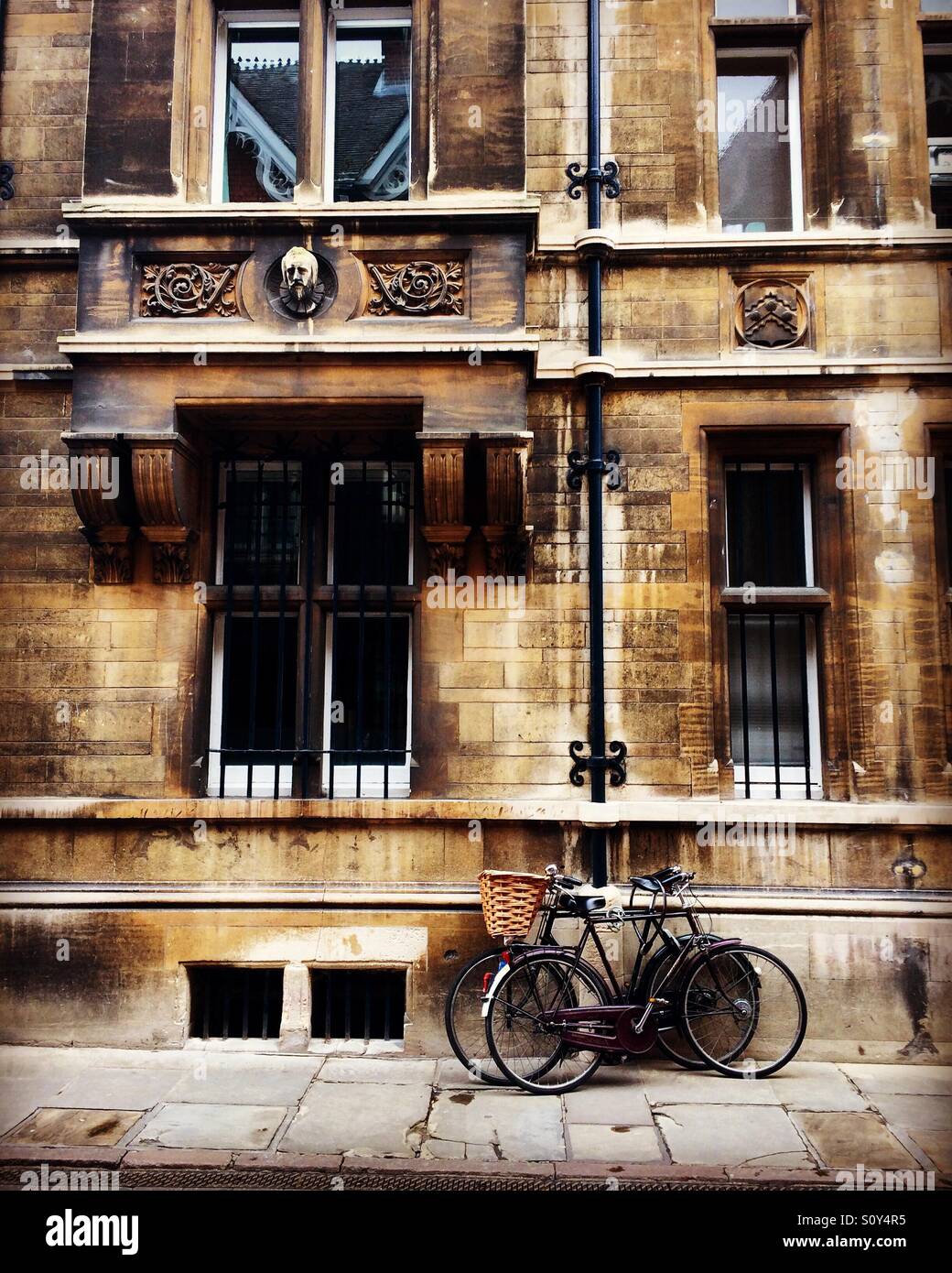 Historical Cambridge city building with bicycles chained to a drainpipe. Stock Photo