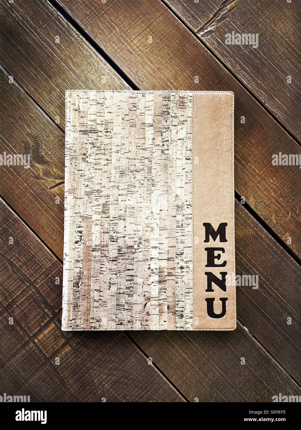 Closed menu book on a wooden table - Smartphone Captured Stock Image