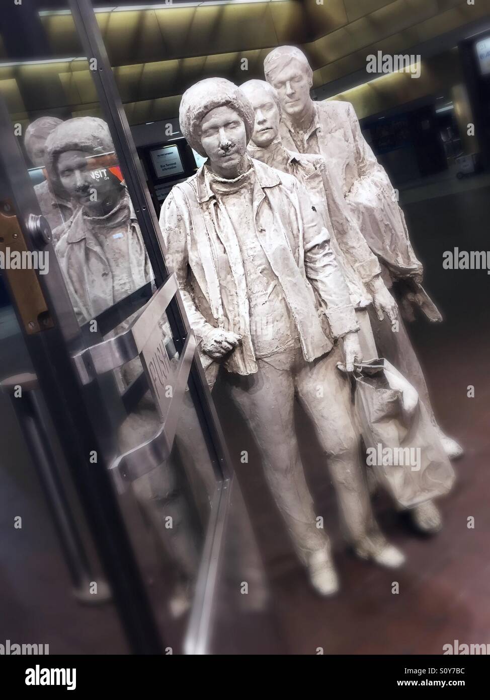 The life-size sculpture of three travelers in line at a boarding gate is on permanent exhibit and the artist is George Siegel. - Smartphone Captured Stock Image