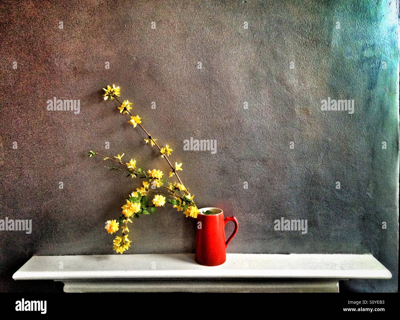 Yellow flowers in a jug on the mantelpiece Stock Photo