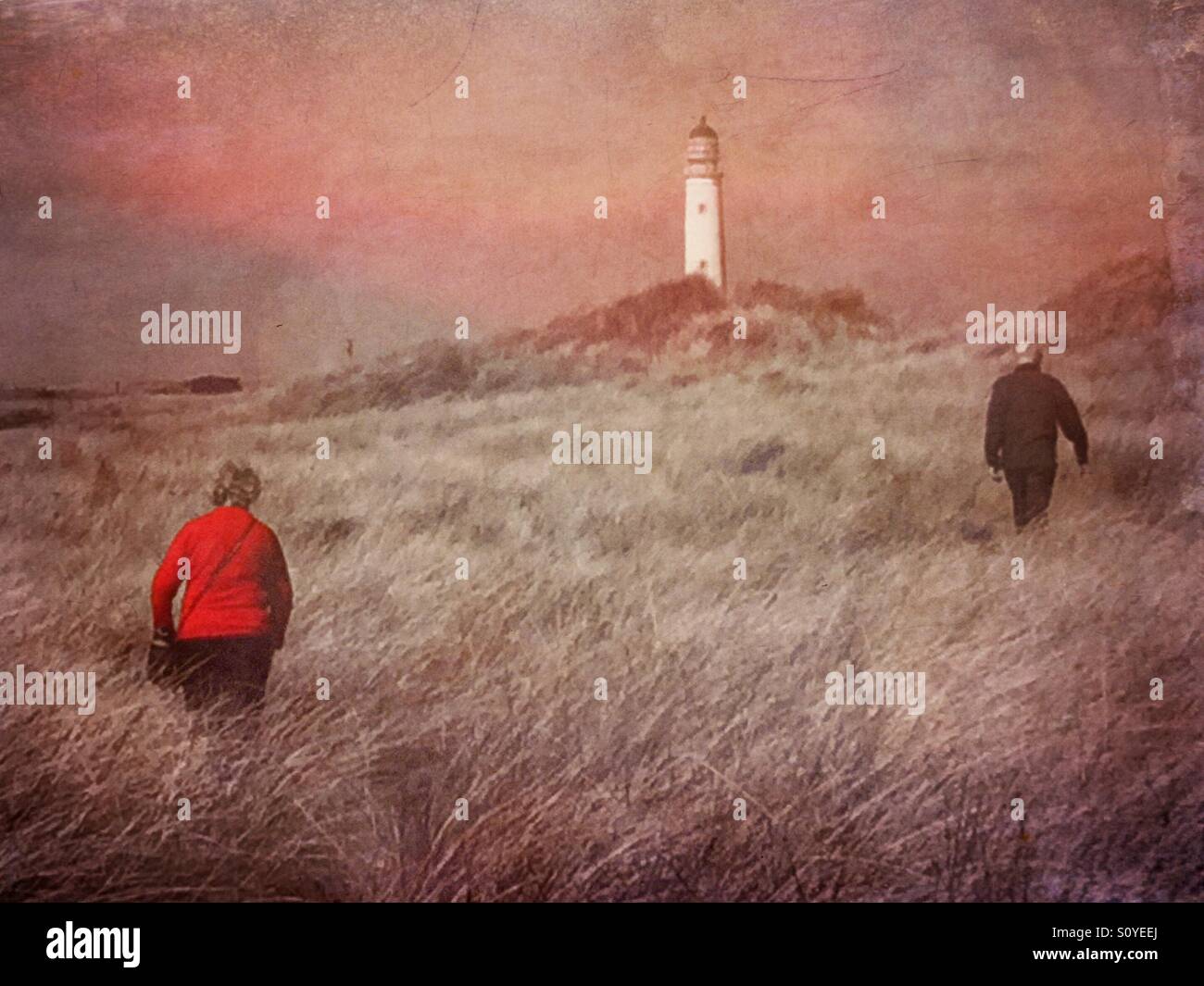 Making your way to the lighthouse. People walking the path through the dunes. Stock Photo