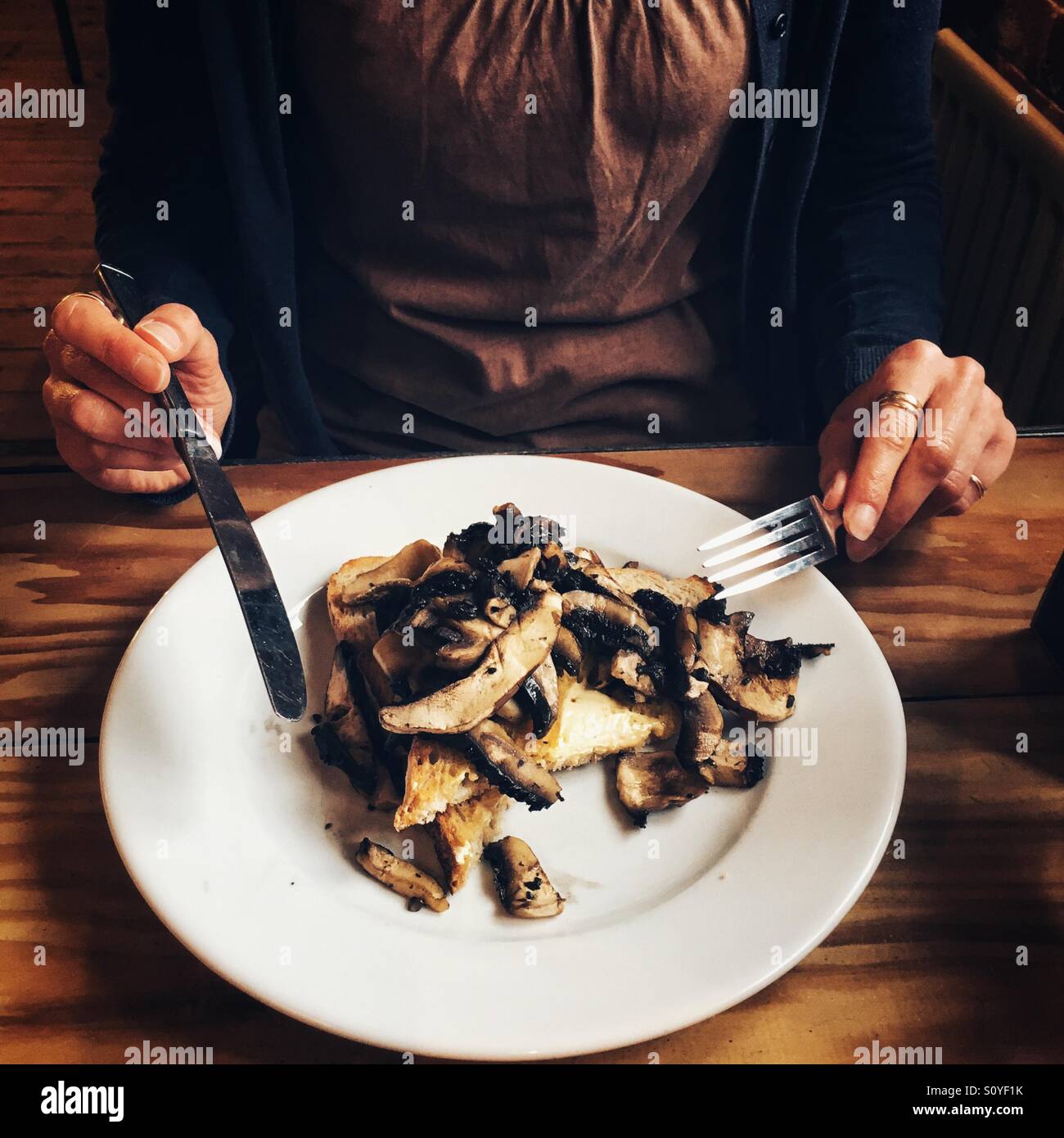 Woman eating mushrooms on sourdough toast - Smartphone Captured Stock Image