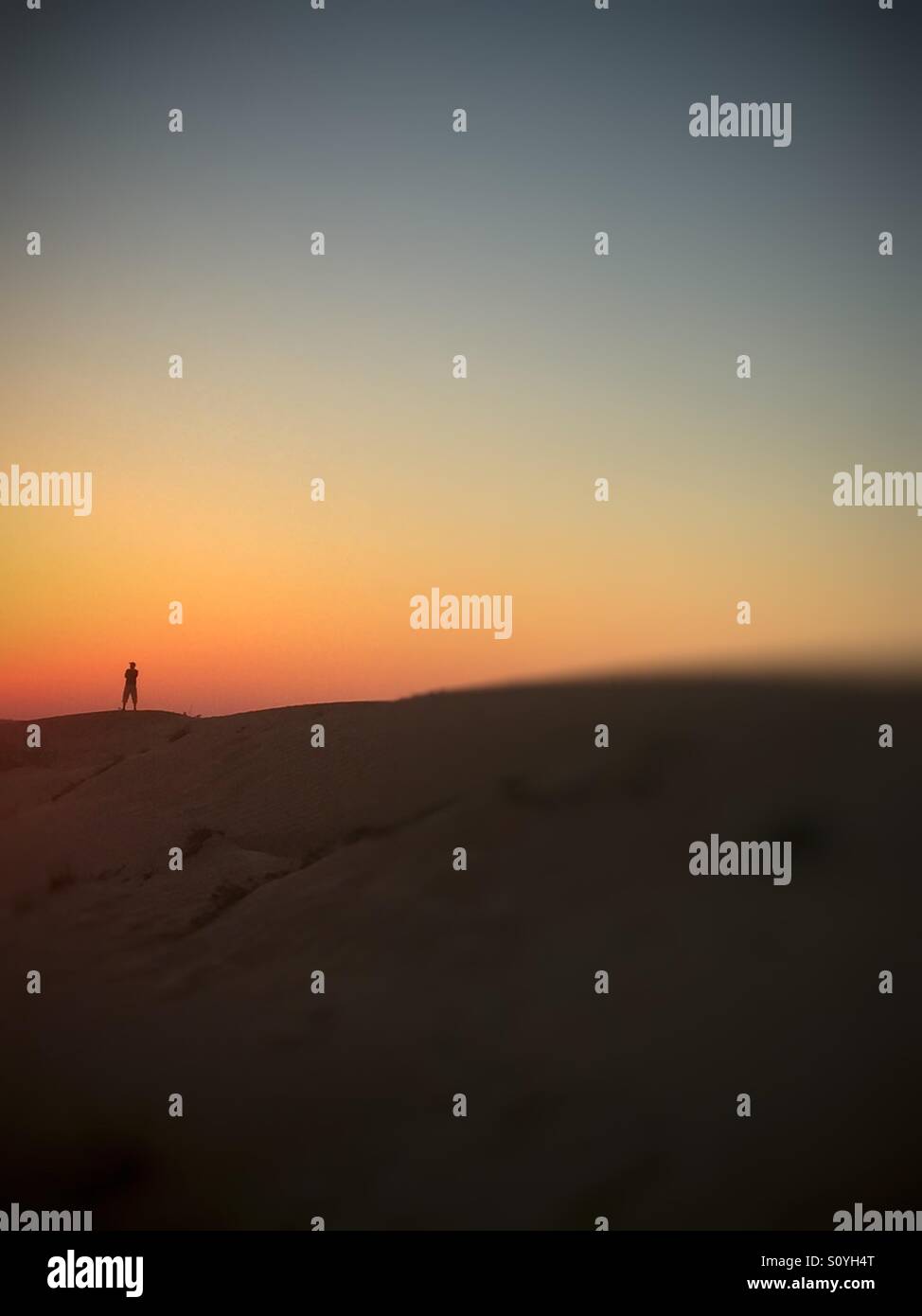 Silhouette of a man standing at sunset in desert blurred - Smartphone Captured Stock Image