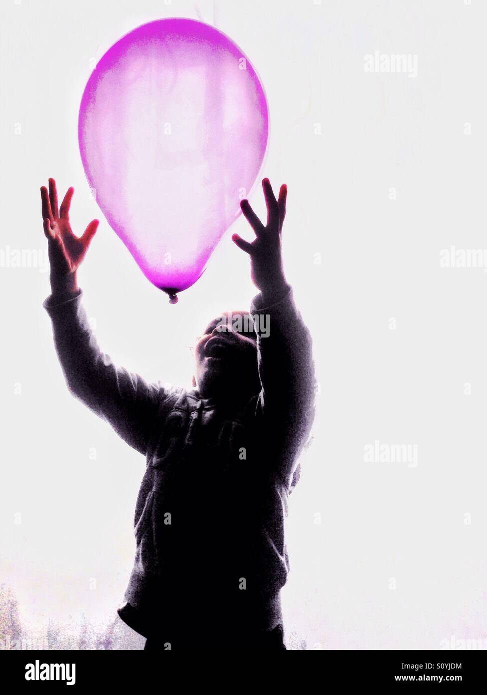 Boy catching a Pink balloon. Stock Photo