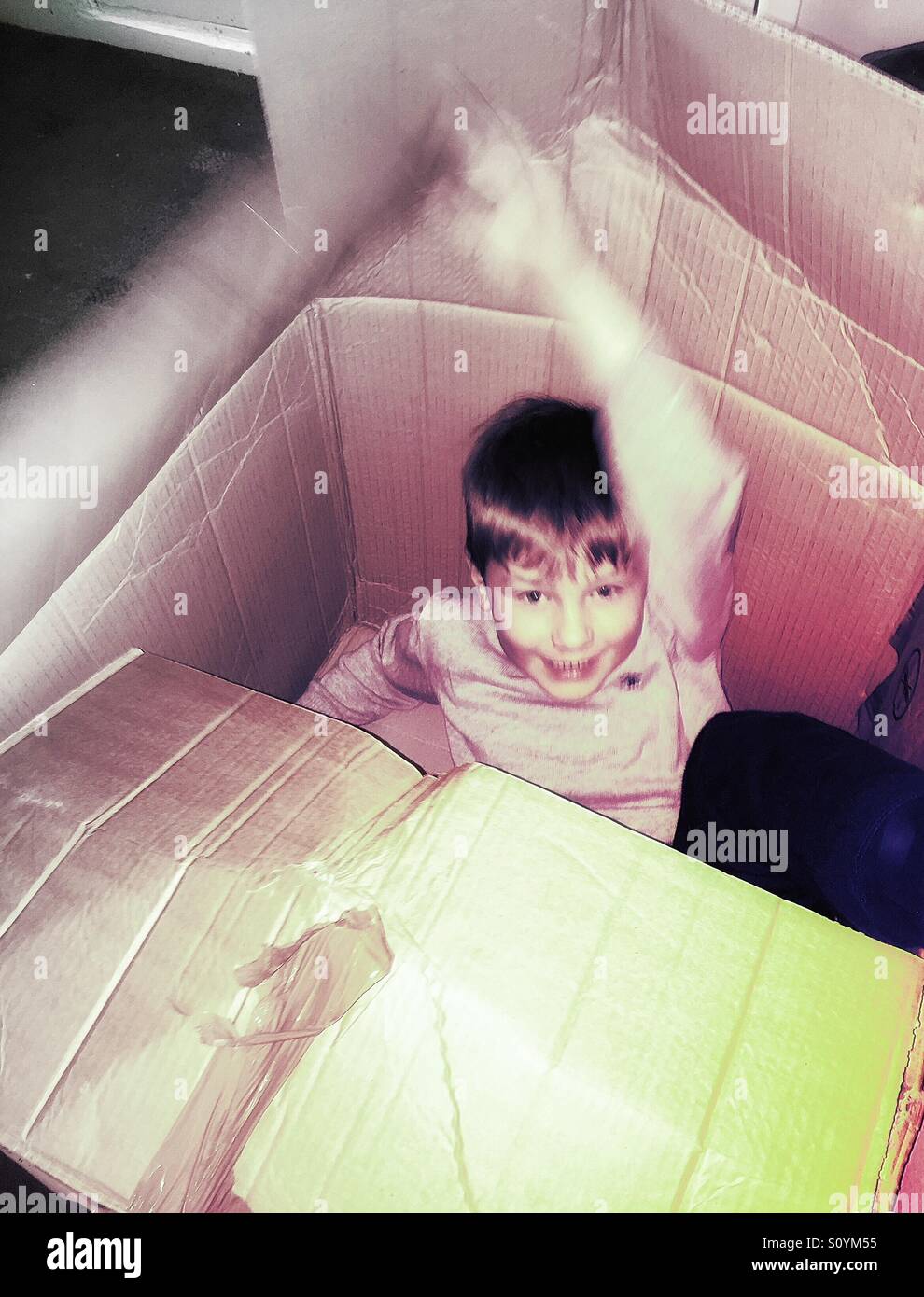 Boy bursting out of a cardboard box. Stock Photo