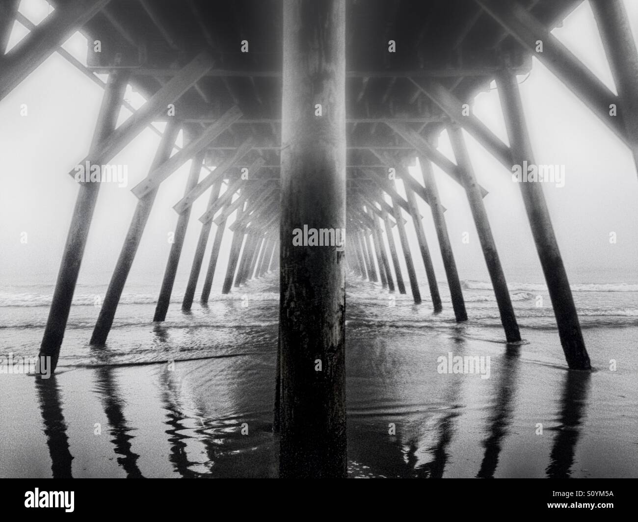 Heavy dense fog surrounds a fishing pier at the Atlantic Ocean in Myrtle Beach South Carolina. Stock Photo