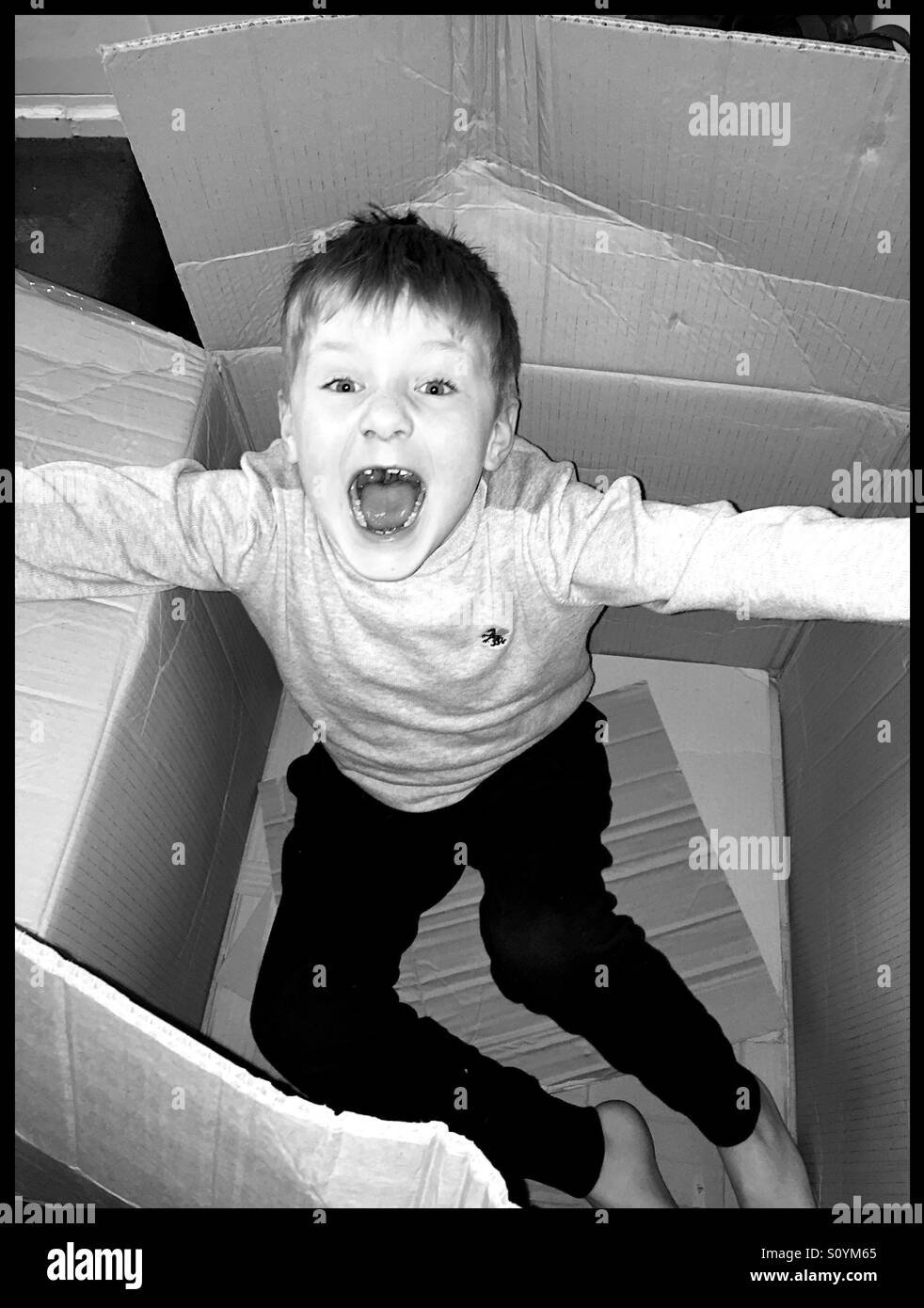 Boy bursting out of a cardboard box Stock Photo