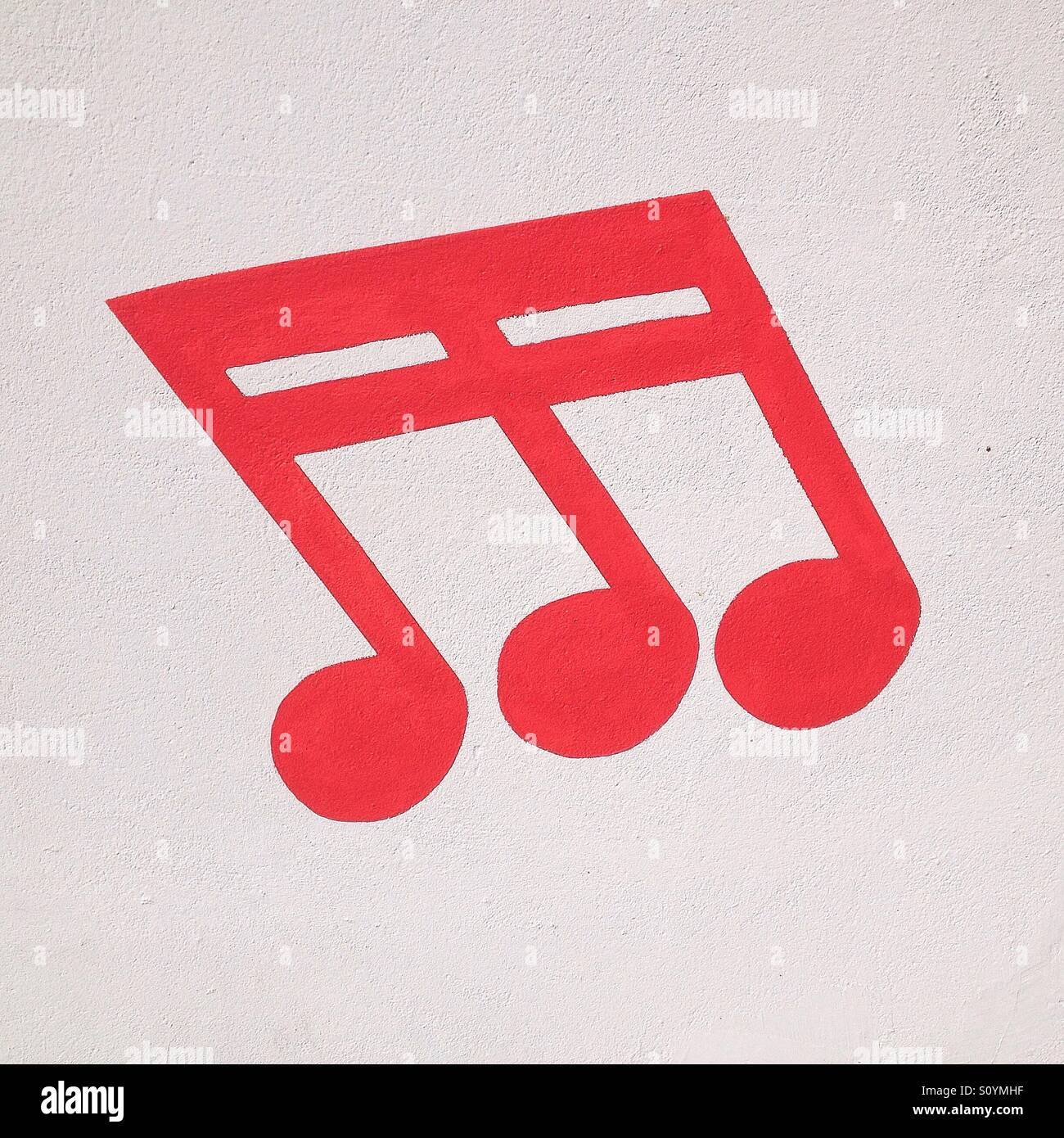 Red musical note painted on a white wall - Smartphone Captured Stock Image