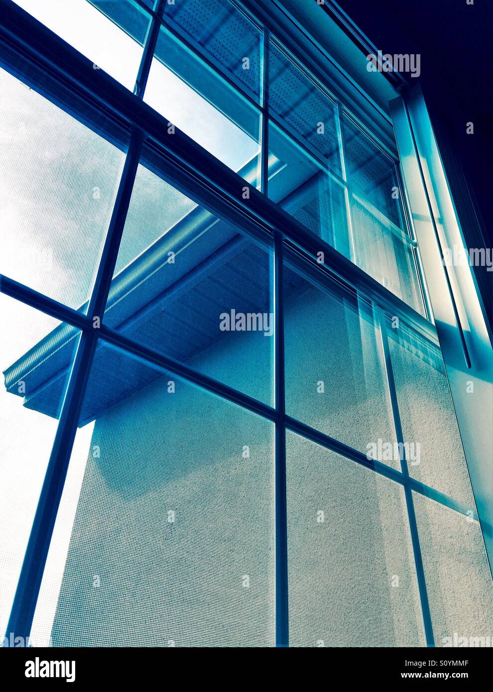 Window view with building detail in muted blue tones - Smartphone Captured Stock Image