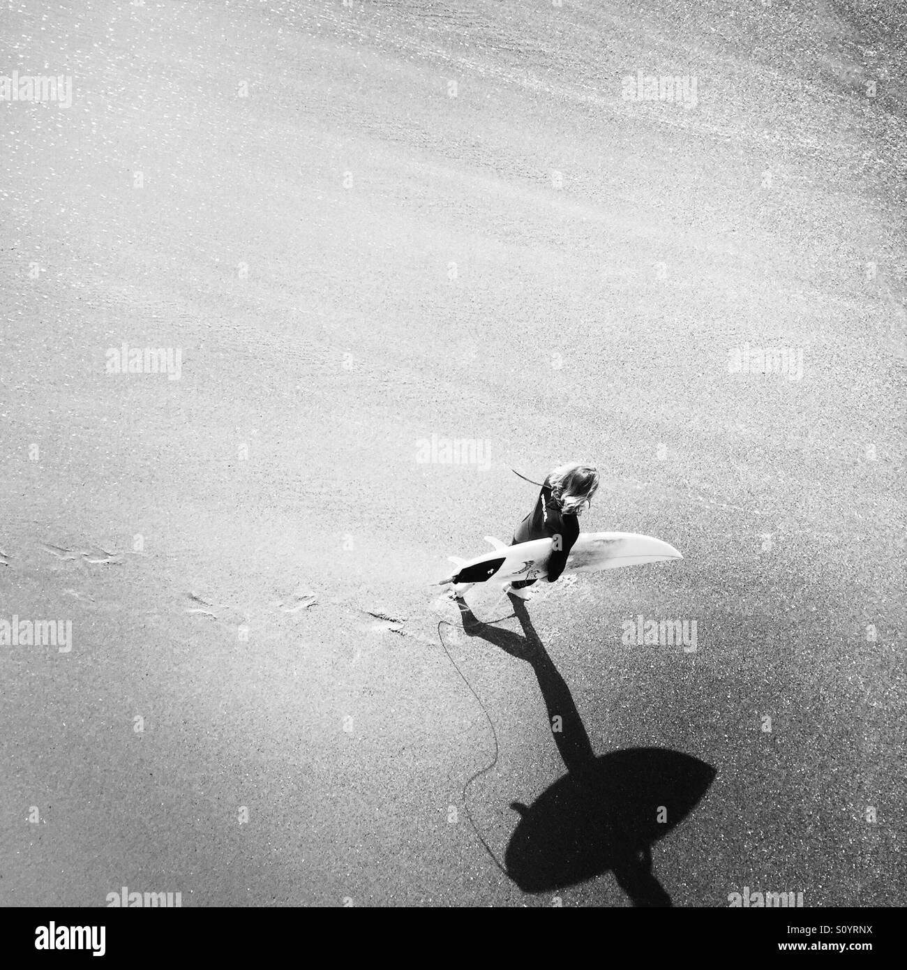 A male surfer walks into the surf. Manhattan Beach, California USA. - Smartphone Captured Stock Image