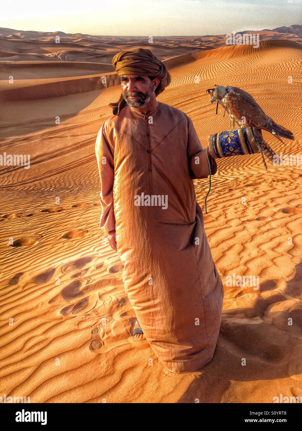 Middle aged man holding a falcon in the dessert Stock Photo