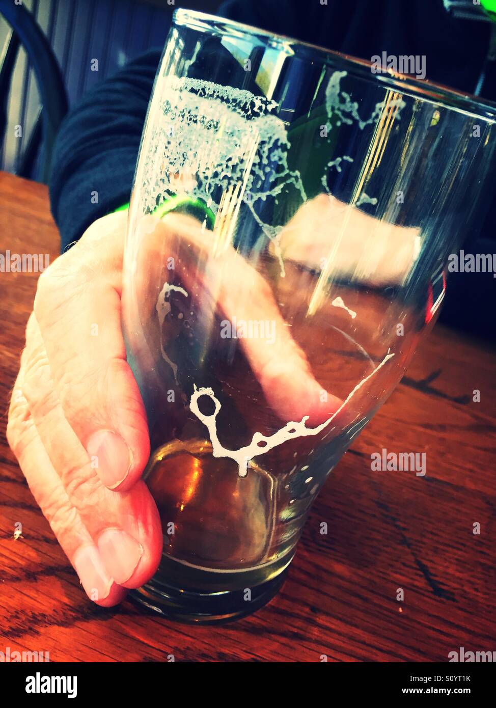 Empty beer glass being placed on bar by a man - Smartphone Captured Stock Image