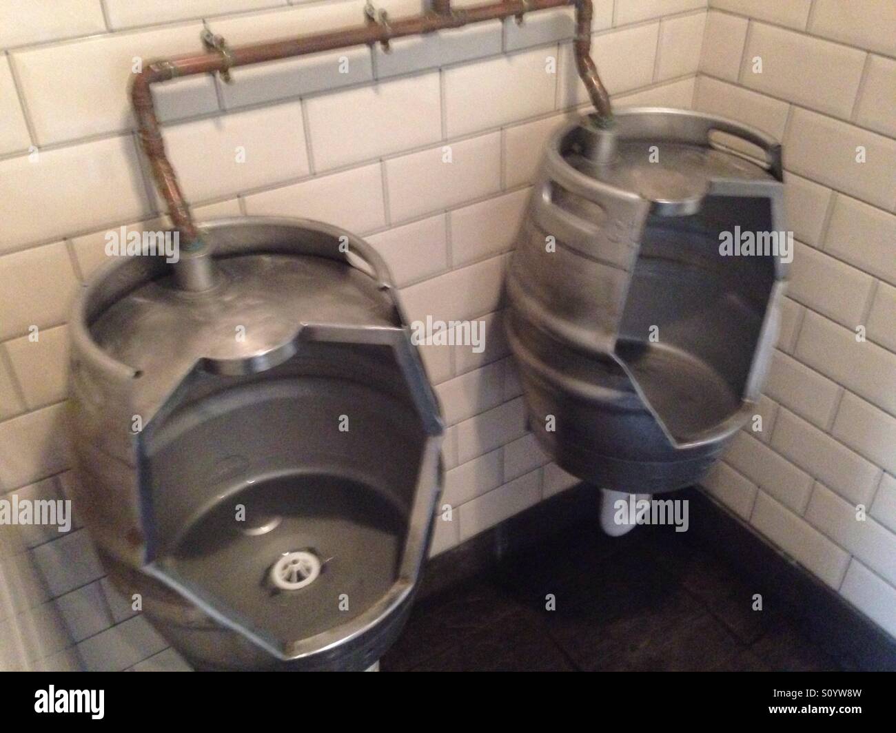 Pub men's urinals made from beer kegs Stock Photo