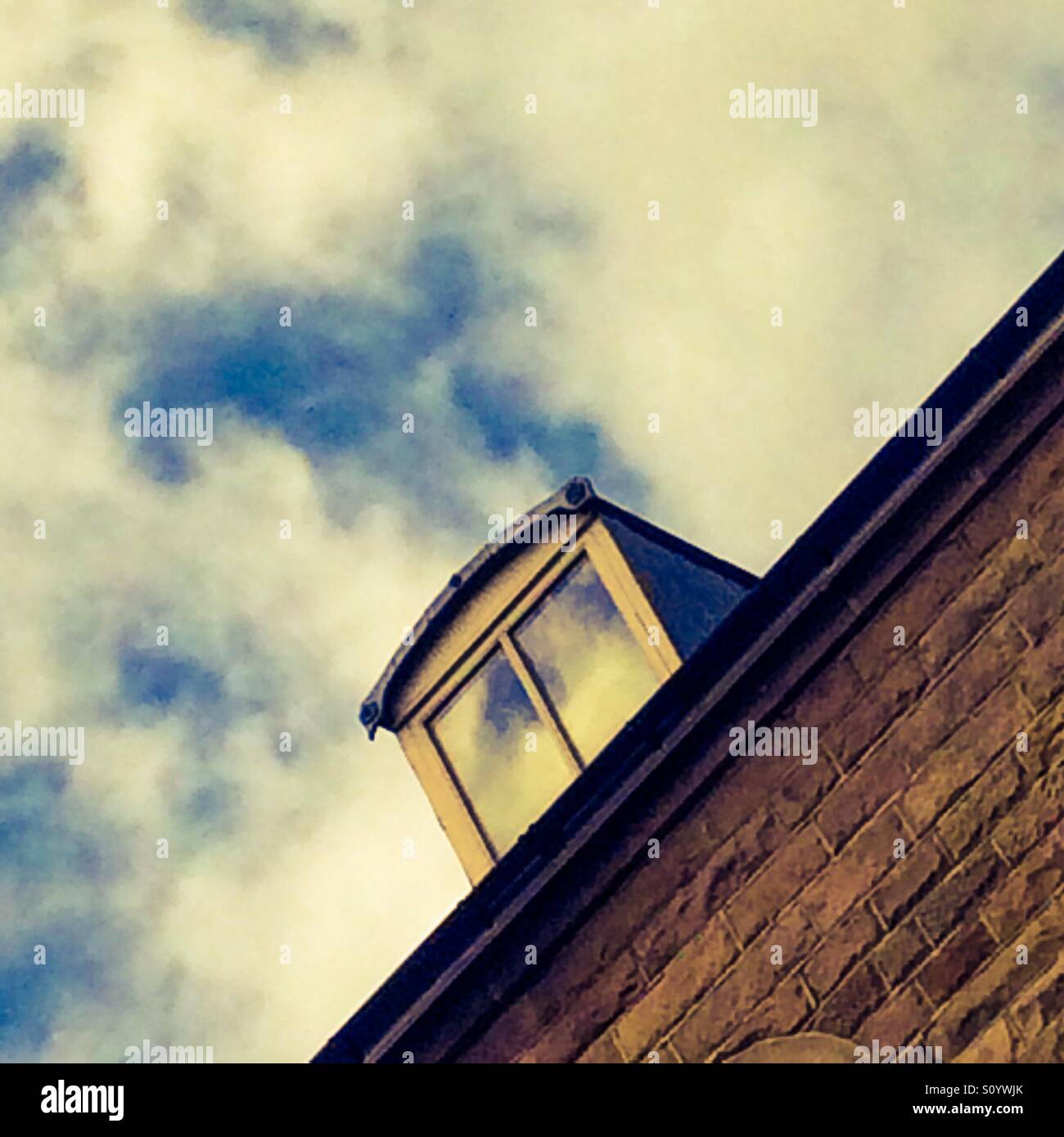 View looking up at the dormer window of a house with sky behind - Smartphone Captured Stock Image