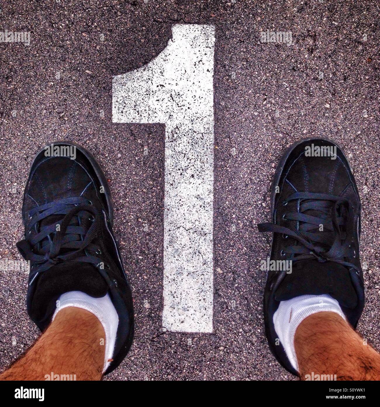 Man feet near the number 1 on a parking lot. - Smartphone Captured Stock Image