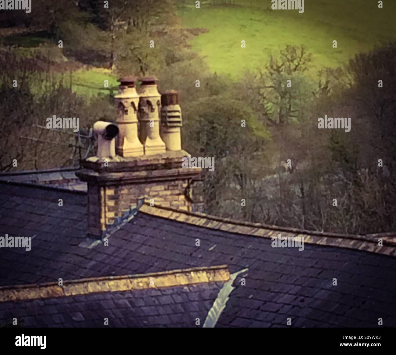 View across rooftop towards a chimney stack with green hills behind - Smartphone Captured Stock Image